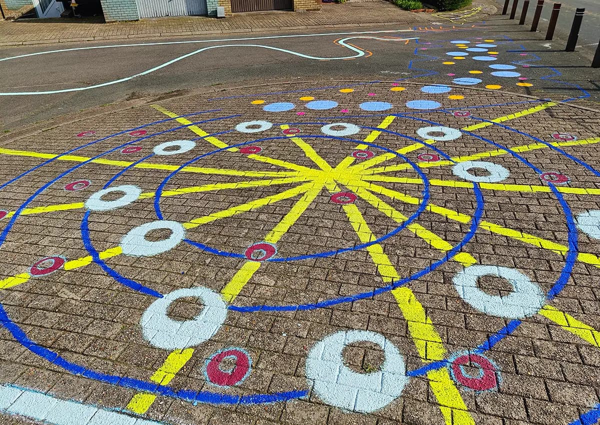 Rond speelveld op de klinkers: blauwe cirkels, gele stralen en witte en rode ringen om van ring naar ring te springen.