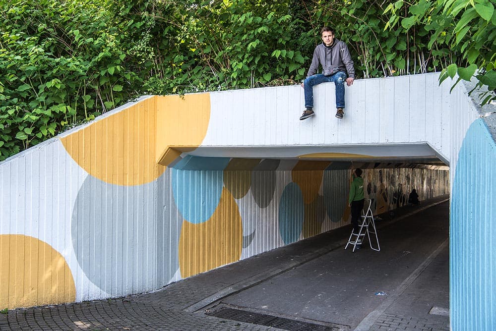 Op de tunnel poseren, een idee van de fotograaf. Onder mij gele, grijze en blauwe cirkels, binnen schildert iemand verder.